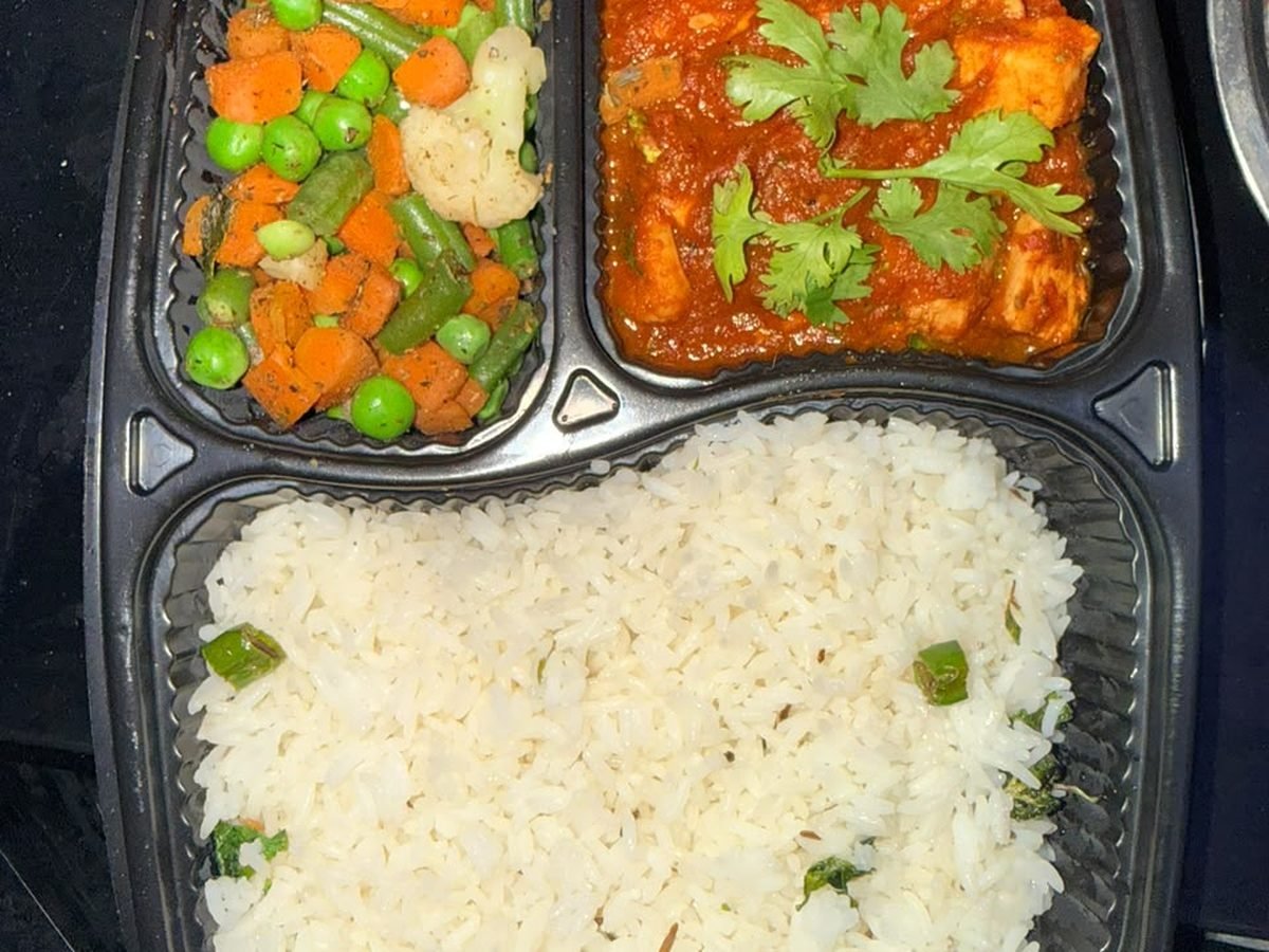 Paneer masala thali box: paneer in tomato gravy, jeera rice and mixed vegetables in a three-compartment tray